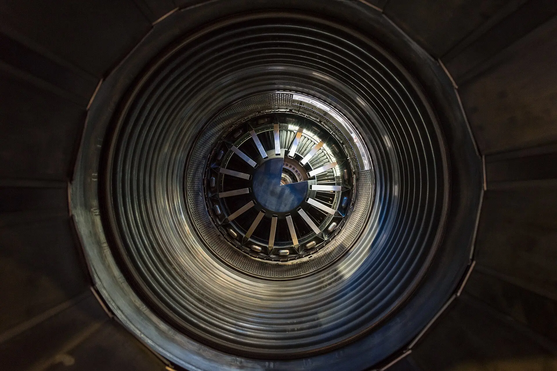 View into the afterburner section of a jet engine: concentric metal rings leading to the turbine blades.