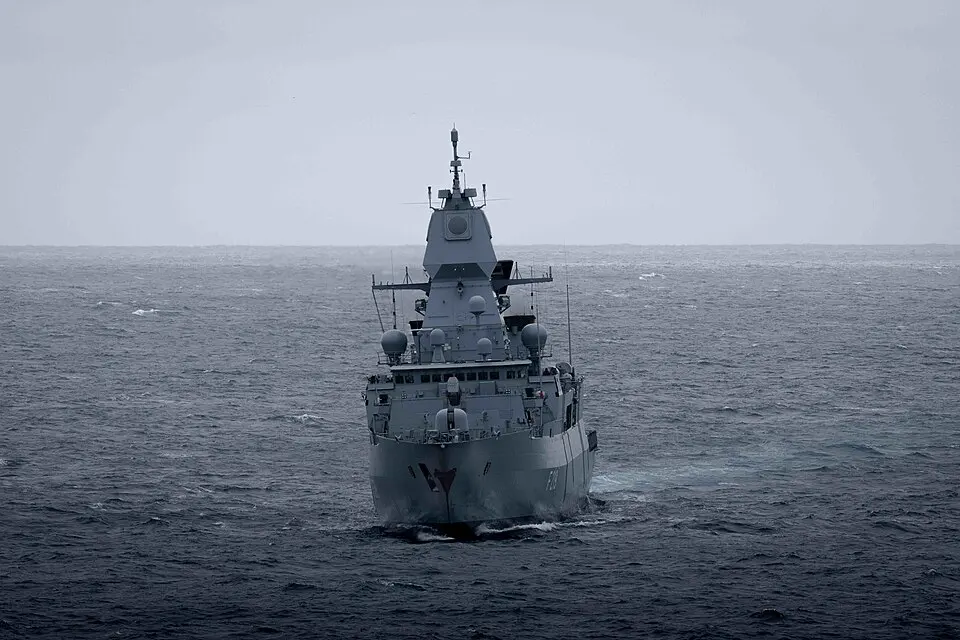 A grey air-defence frigate seen bow-on in a dark, overcast sea.